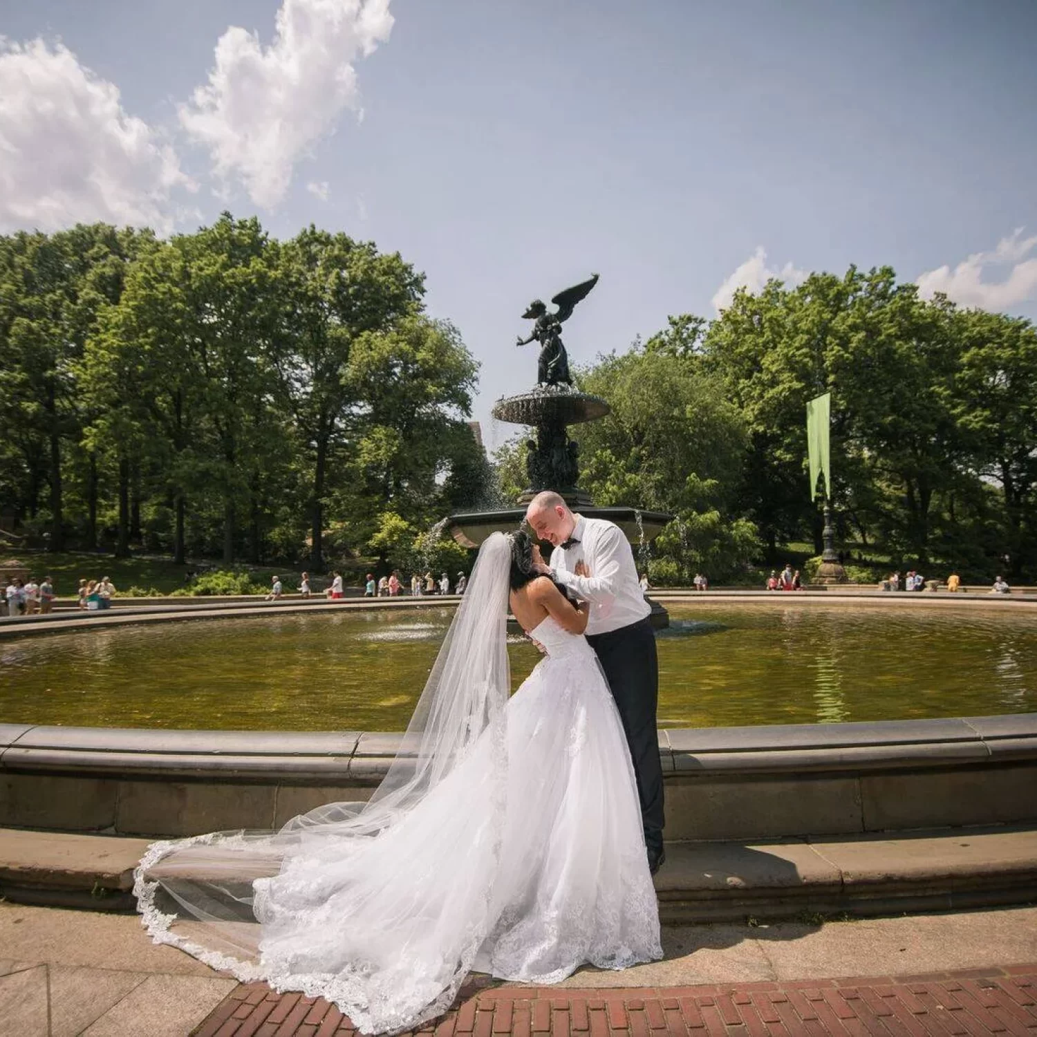 Bride and groom posing in front of a grand fountain at Central Memorial Park, an elegant urban park for classic wedding portraits in Calgary.